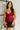 Front view of model wearing the Sasha Burgundy Sequin Strappy Romper that has dark red knit fabric with monochromatic sequins, a v-neckline, adjustable straps, an open back, and a back zipper.