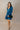 Full body front view of model wearing the Lottie Blue Satin Long Sleeve Mini Dress that has deep blue satin fabric, mini length, a v-neck, and long balloon sleeves.