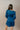 Back view of model wearing the Lottie Blue Satin Long Sleeve Mini Dress that has deep blue satin fabric, mini length, a v-neck, and long balloon sleeves.