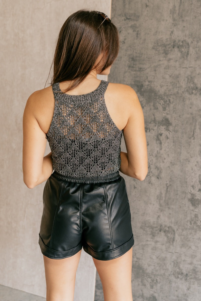 Back view of model wearing the Ava Black & Silver Textured High Neck Tank which features black and silver textured knit fabric, a high neckline and a sleeveless design.