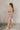 Full body side view of model wearing the Britney Purple Camo Strapless Mini Dress that has purple sheer fabric, camoflauge print, a slit on the side with ruffle details, and a strapless neckline.