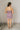 Full body back view of model wearing the Britney Purple Camo Strapless Mini Dress that has purple sheer fabric, camoflauge print, a slit on the side with ruffle details, and a strapless neckline.