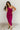 Full body front view of model wearing the Tiffany Fuchsia Ruched One-Shoulder Midi Dress that has fuchsia stretchy semi-satin fabric, ruched details, a one-shoulder neckline, and a side zipper.