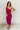 Full body front view of model wearing the Tiffany Fuchsia Ruched One-Shoulder Midi Dress that has fuchsia stretchy semi-satin fabric, ruched details, a one-shoulder neckline, and a side zipper.