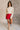 Full body view of model wearing the Ruby Red Slit Detail Mini Skort which features red lightweight fabric, slit on the side, red shorts lining, mini length and monochromatic back zipper with hook closure.