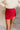 Front view of model wearing the Ruby Red Slit Detail Mini Skort which features red lightweight fabric, slit on the side, red shorts lining, mini length and monochromatic back zipper with hook closure.