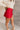 SIde view of model wearing the Ruby Red Slit Detail Mini Skort which features red lightweight fabric, slit on the side, red shorts lining, mini length and monochromatic back zipper with hook closure.