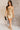 Full body view of model wearing the Amber Gold Cowl Neckline Sleeveless Mini Dress which features gold shimmer fabric, mini length, gold lining, a cowl neckline, adjustable straps, and a monochromatic back zipper with a hook closure.