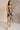 Full body view of model wearing the Amber Gunmetal Cowl Neckline Sleeveless Mini Dress which features gunmetal grey shimmer fabric, mini length, black lining, a cowl neckline, adjustable straps, and a monochromatic back zipper with a hook closure.