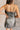 Back view of model wearing the Amber Gunmetal Cowl Neckline Sleeveless Mini Dress which features gunmetal grey shimmer fabric, mini length, black lining, a cowl neckline, adjustable straps, and a monochromatic back zipper with a hook closure.