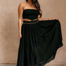 Full body view of model wearing the Mila Black Pleated Midi Skirt which features black pleated sheer fabric, black lining, midi length, and an elastic waistband with ruffle details.