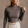 Front view of model wearing the Raelynn Mocha Brown Ribbed Long Sleeve Top which features mocha brown ribbed fabric, a high neckline, and long sleeves.