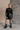 Full body front view of model wearing the Anastasia Black Embellished Mesh Top that has black mesh fabric, silver embellishments, exposed seam details, a high neckline, and long sleeves.