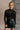 front view of model wearing the Anastasia Black Embellished Mesh Top that has black mesh fabric, silver embellishments, exposed seam details, a high neckline, and long sleeves.