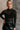 front view of model wearing the Anastasia Black Embellished Mesh Top that has black mesh fabric, silver embellishments, exposed seam details, a high neckline, and long sleeves.
