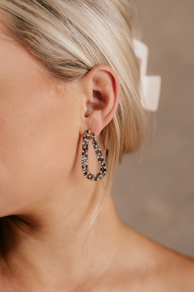 Front view of model wearing the Jenna Multi & Pearl Beaded Earring which features teardrop shaped filled with pearls and multi color rhinestone design, set in gold.