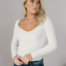 Front view of model wearing the Ember Off White Long Sleeve Ribbed Top which features off white ribbed fabric, a sweetheart neckline, and long sleeves.