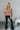 Full body front view of model wearing the Elliana Pink Floral Long Sleeve Top that has a rust, pink, tan and cream floral print, lace details, a v-neck, an open back with a tie , and long puff sleeves.
