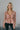 front view of model wearing the Elliana Pink Floral Long Sleeve Top that has a rust, pink, tan and cream floral print, lace details, a v-neck, an open back with a tie , and long puff sleeves.
