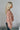Side view of model wearing the Elliana Pink Floral Long Sleeve Top that has a rust, pink, tan and cream floral print, lace details, a v-neck, an open back with a tie , and long puff sleeves.