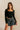 Front view of model wearing the Emeree Black Cropped Long Sleeve Top which features black knit fabric, a cropped waist with a scooped hem, boning details, a square neckline, and long sleeves.