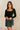 Front view of model wearing the Emeree Black Cropped Long Sleeve Top which features black knit fabric, a cropped waist with a scooped hem, boning details, a square neckline, and long sleeves.