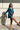Frontal view of model wearing The Elaine Satin Dress features a blue, green satin material, a cowl neckline, long sleeves, an open cowl back with a tie closure, and a mini length.