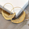 Close-up image of the Flying Free Earrings, which have gold wire hoops with gold metal feathers at the bottom.