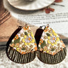 Front view of the In The Groove Earrings, which feature a teardrop shape with a wooden upper portion with mustard and olive flowers and a gold bottom.