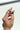 Close-up image of model's hand; model is wearing the Full Bloom Ring Set, which includes 5 varied gold rings.