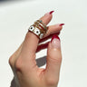 Close-up image of model's hand; model is wearing the Full Bloom Ring Set, which includes 5 varied gold rings.