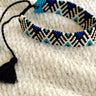 Close image of the Forever Yours Beaded Bracelet that features black, white, and blue beading with an adjustable black tasseled tie.