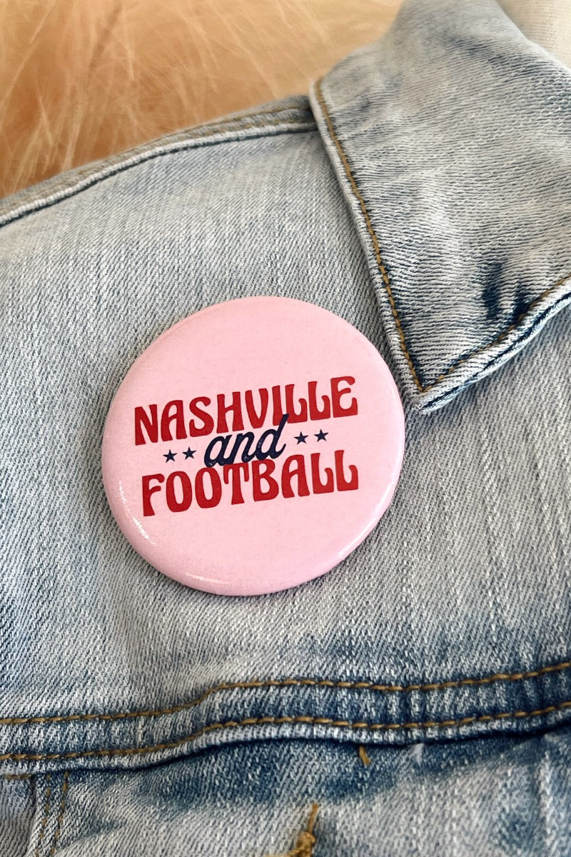 Close up image of the Nashville and Football Button which features a pink button with red and navy text that says "Nashville and Football" with stars.