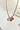 Close up view of the Flower Dreams Necklace which features gold chain link with two pick flowers and one white flower.