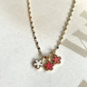 Close up view of the Flower Dreams Necklace which features gold chain link with two pick flowers and one white flower.