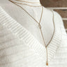 Full view of the Be Truthful Necklace which features triple layered necklace with leave shaped stone and gold link.