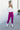 Full body front view of model wearing the Be Fearless Pants, that have magenta corduroy fabric, two front pockets, a paperbag waist with a tie, a zipper and button closure, and straight legs