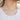 Close up view of model wearing the Fairytale Flower Necklace which features gold linked chain with beige flowers. 