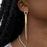 Close up view of model wearing the One And Only Gold Earring which features gold plated dangle strips attached to a small gold plated circle. 