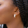 Close up view of model wearing the In The Magic Mini Hoops which features blue, purple and cream beaded mini hoops. 