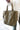 Close up view of model holding the Time To Go Purse in Olive that has pleather with diamond stitching, a middle zipper compartment with pouches inside, and compartments on each side. 