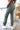 Side view of model wearing the On The Go Jogger Pants, that have olive fabric, ruched detailing on the sides, two front pockets, two back pockets, an elastic waist band with a tie closure, and elastic ankles