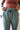 Close upper front view of model wearing the On The Go Jogger Pants, that have olive fabric, ruched detailing on the sides, two front pockets, two back pockets, an elastic waist band with a tie closure, and elastic ankles