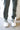 Close lower front view of model wearing the On The Go Jogger Pants, that have olive fabric, ruched detailing on the sides, two front pockets, two back pockets, an elastic waist band with a tie closure, and elastic ankles