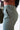 Close upper side view of model wearing the On The Go Jogger Pants, that have olive fabric, ruched detailing on the sides, two front pockets, two back pockets, an elastic waist band with a tie closure, and elastic ankles