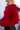 Side view of model wearing the Always A Hit Sweater which features red ribbed knit fabric, a cropped waist, a round neckline and balloon sleeves with cuffed wrists.