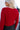 Close up back view of model wearing the Always A Hit Sweater which features red ribbed knit fabric, a cropped waist, a round neckline and balloon sleeves with cuffed wrists.