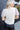 Back view of model wearing the Ready To Sparkle Top which features cream knit fabric, a round neckline, and short sleeves with monochromatic sequins.