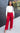 Full body view of model wearing the Endless Love Pant which features red satin fabric, geometric pattern, zipper and hook closure, two back pockets, belt loops and straight wide leg.
