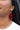 Close up view of model wearing the Let's Party Earrings in Red which features red metallic tassels. 